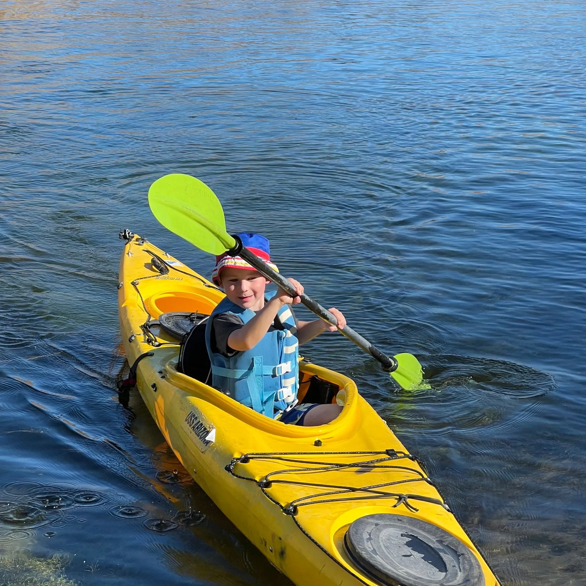 Person paddling a yellow kayak on a calm body of water.
