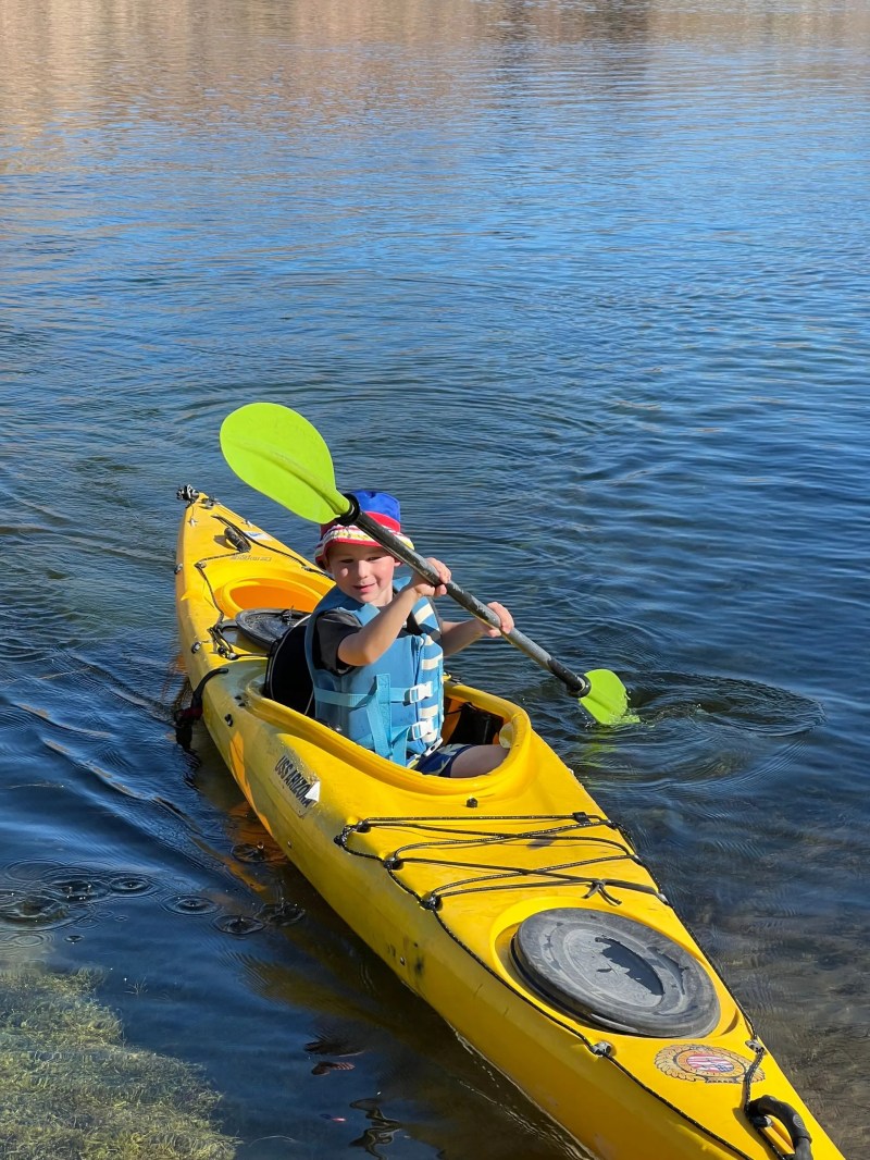 Person paddling a yellow kayak on a calm body of water.